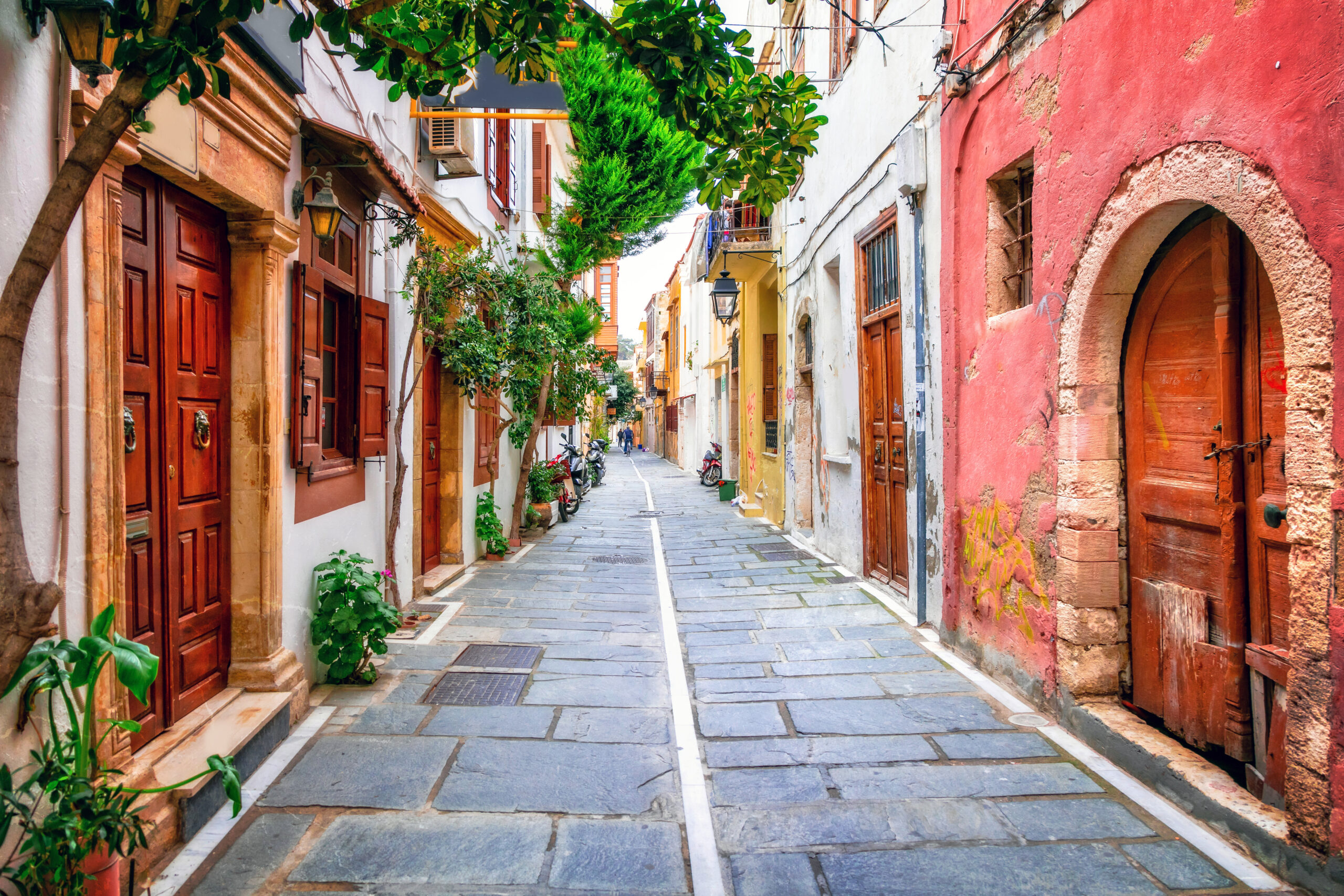 picturesque narrow street in old town rethymno with pink walls and flowers — charming traditional greek architecture of crete island without people, greece