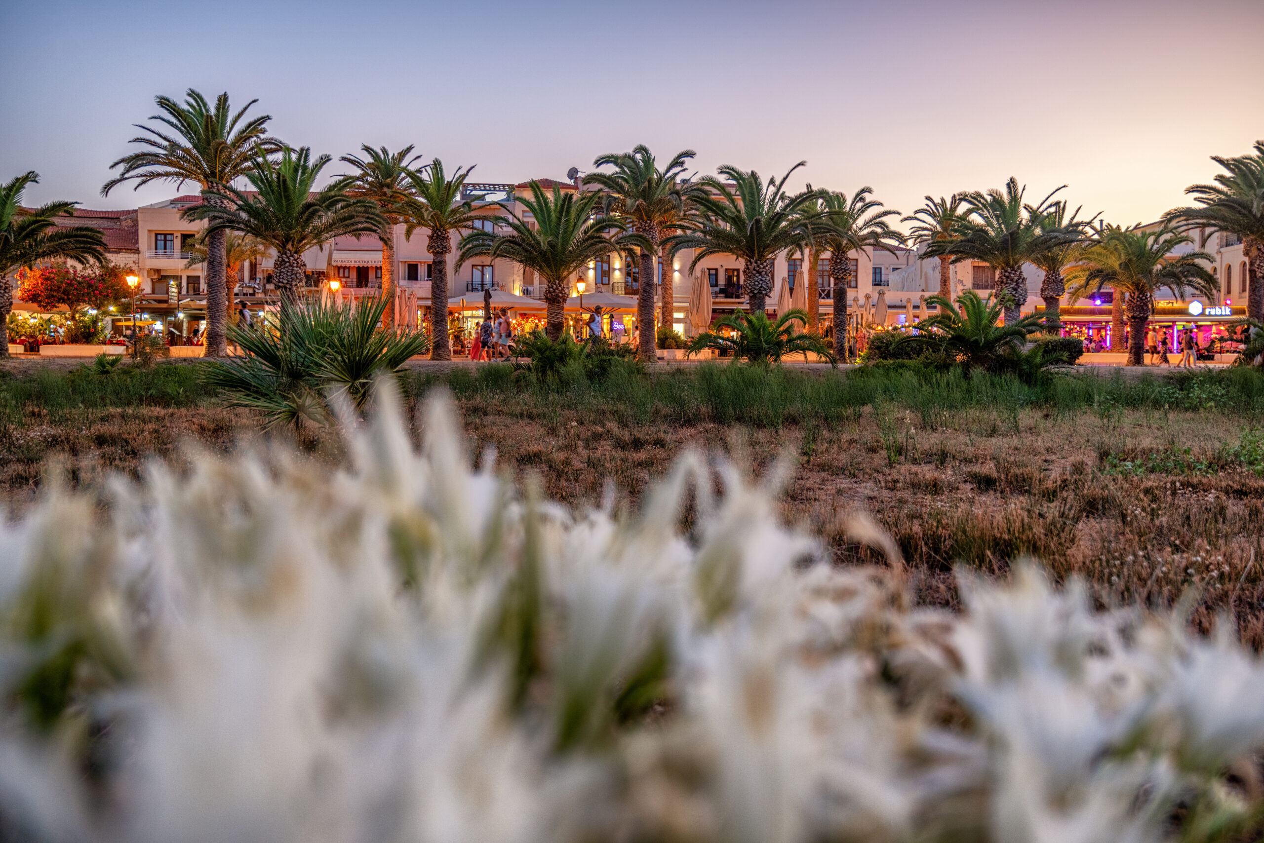 palm lined street with restaurants in rethymno crete at sunset