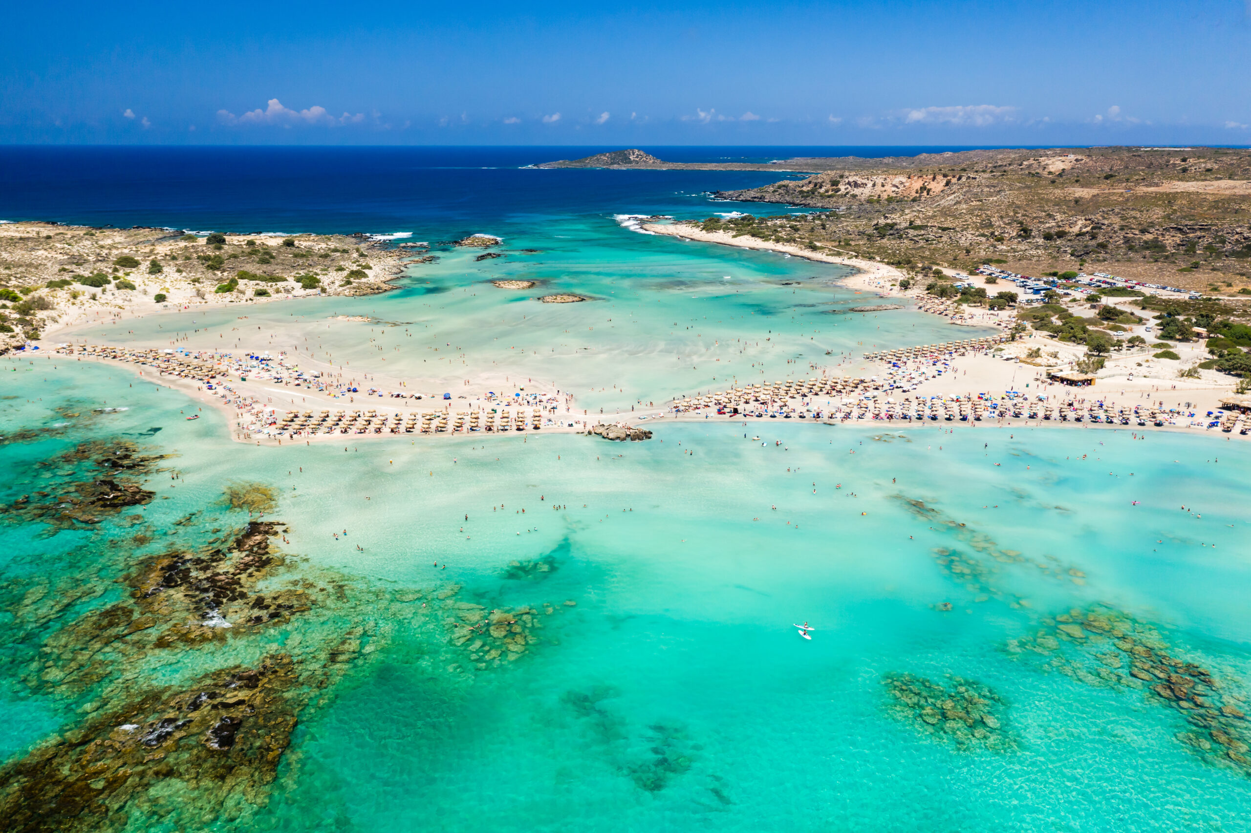aerial view of a beautiful but busy sandy beach and shallow lagoons surrounded by clear, blue ocean (elafonissi, crete)