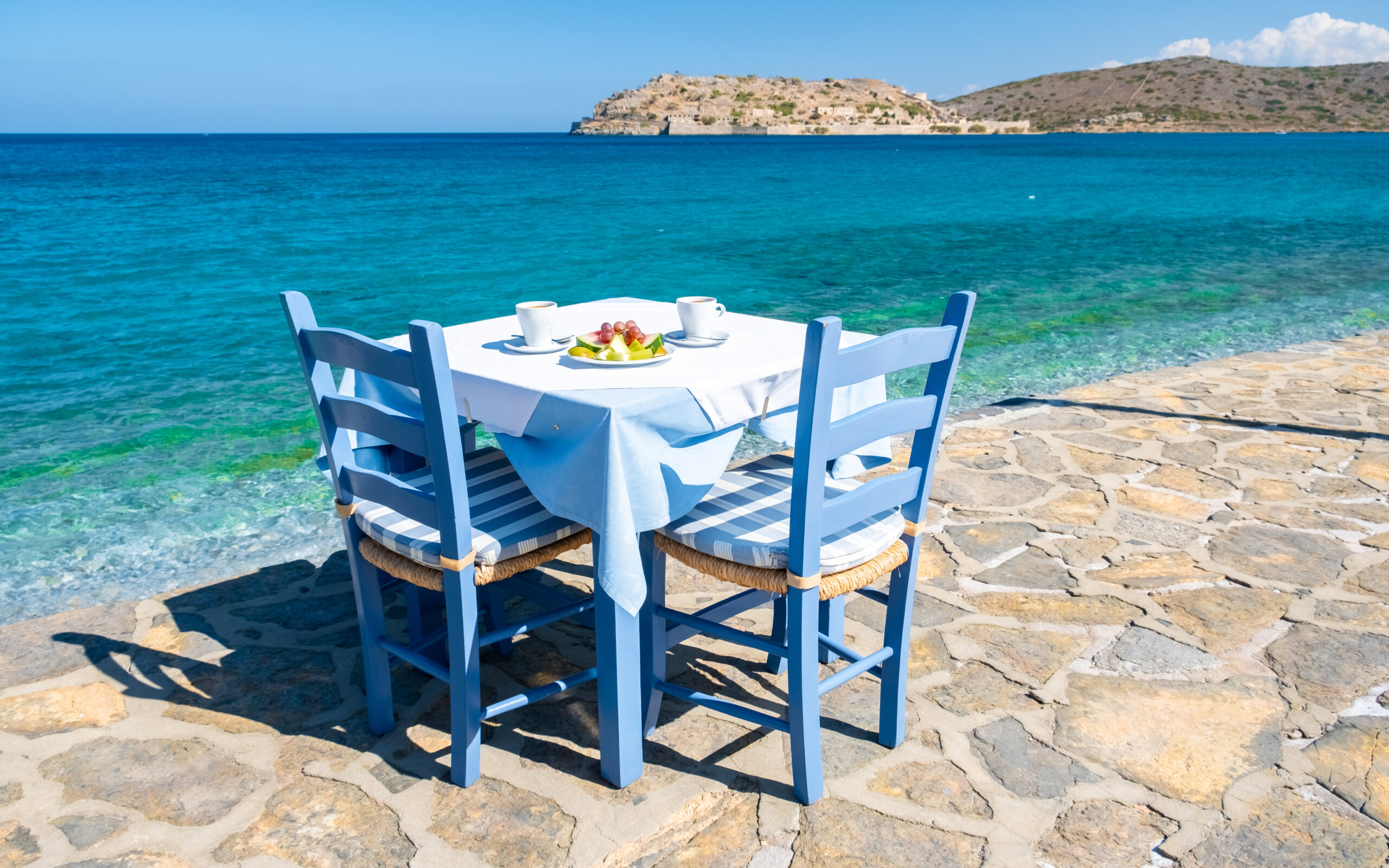 crete greece plaka lassithi with is traditional blue table and chairs and the beach in crete greece.